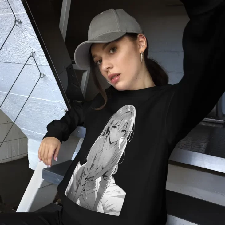 A woman wearing a gray cap and black sweatshirt with a manga design of an anime girl on bed