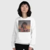 A woman wearing a white sweatshirt with a design of a 90s anime girl in the beach in a retro vintage style