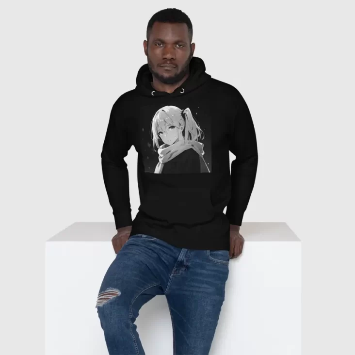 A man sitting on a white block wearing a black hoodie with a manga design of an anime girl in winter